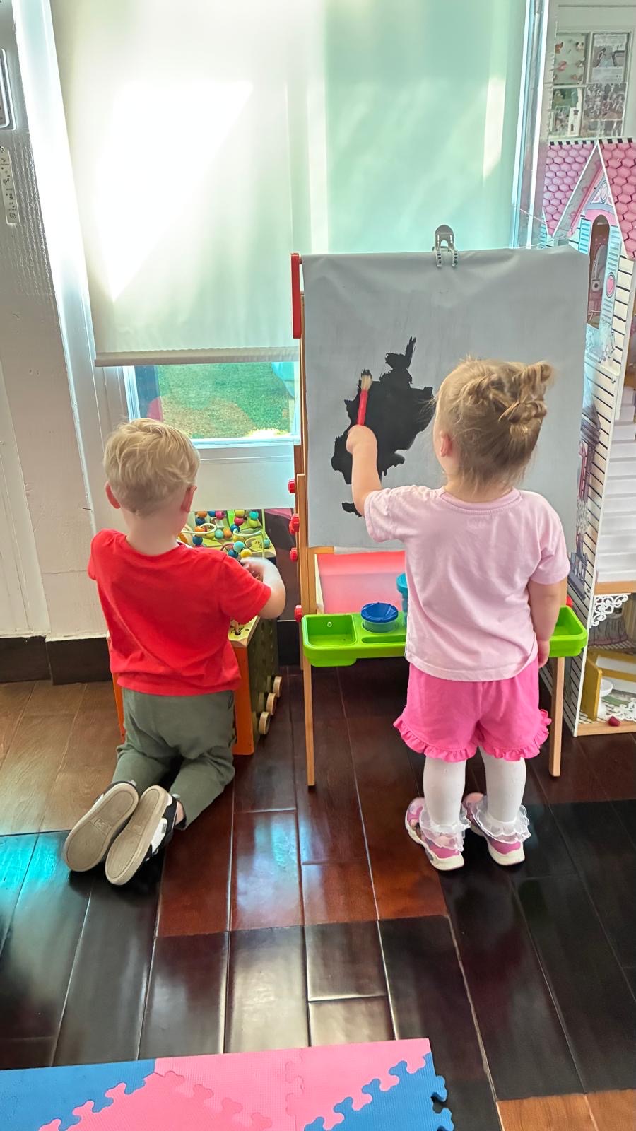 Children painting at an indoor easel