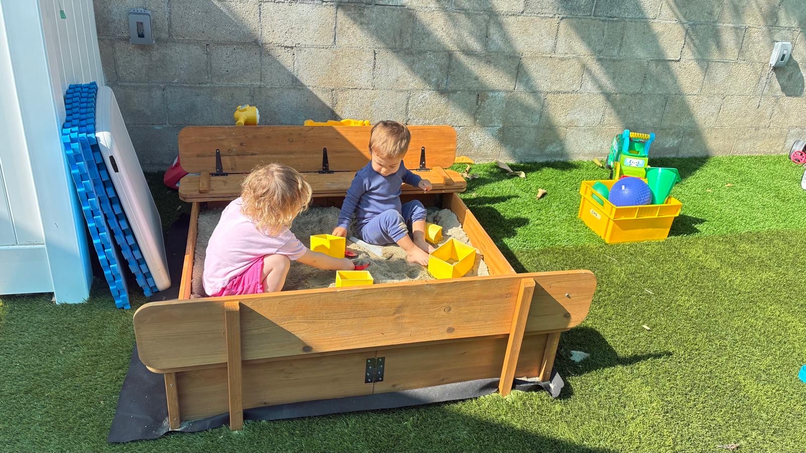 Children playing in a sandbox in the outdoor daycare yard